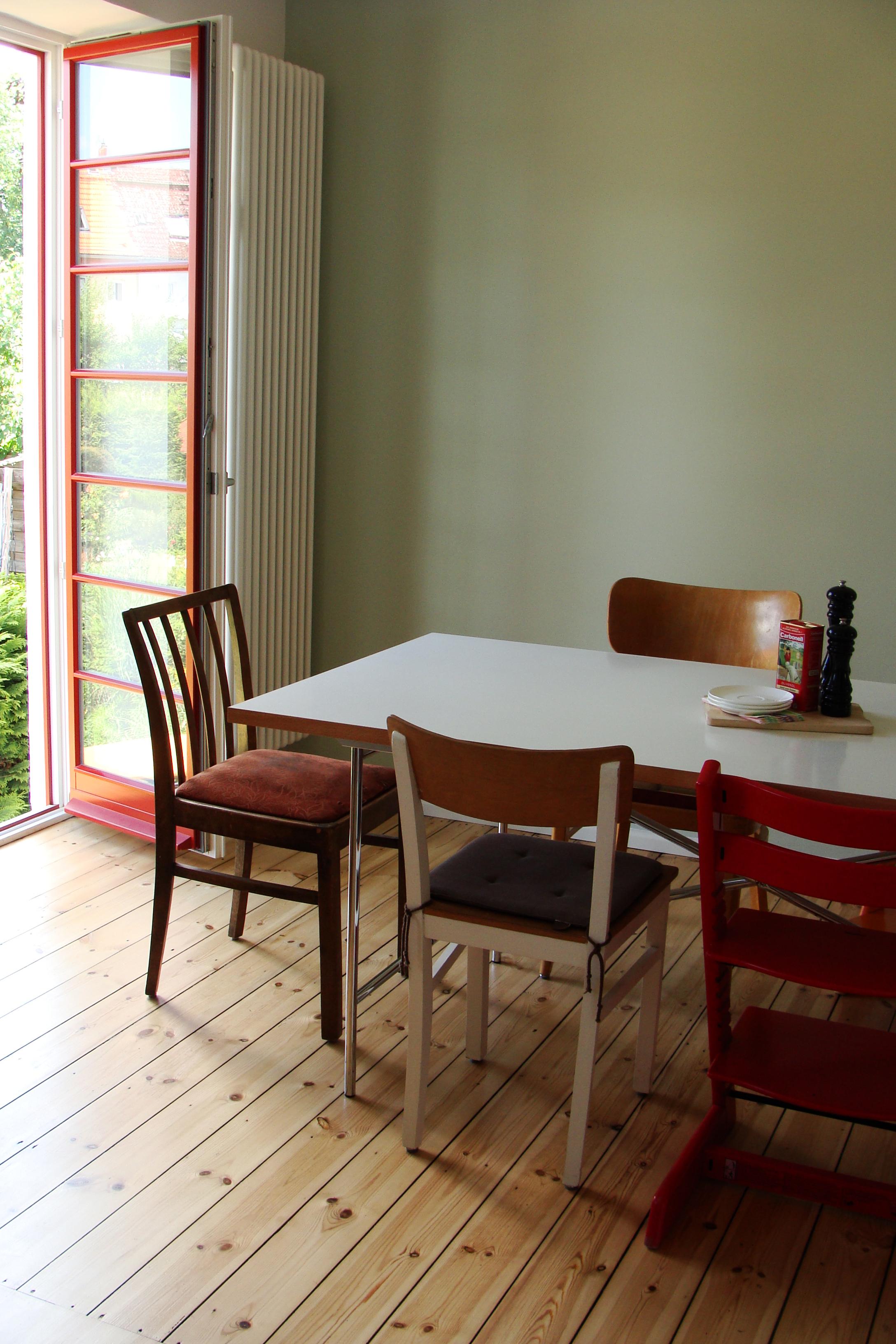 Essplatz mit grüner Wand und roten Fenstern #küche #dielenboden #wandfarbe #vintage #esstisch #esszimmerstuhl #essplatz #grünewandfarbe ©Mareike Kühn