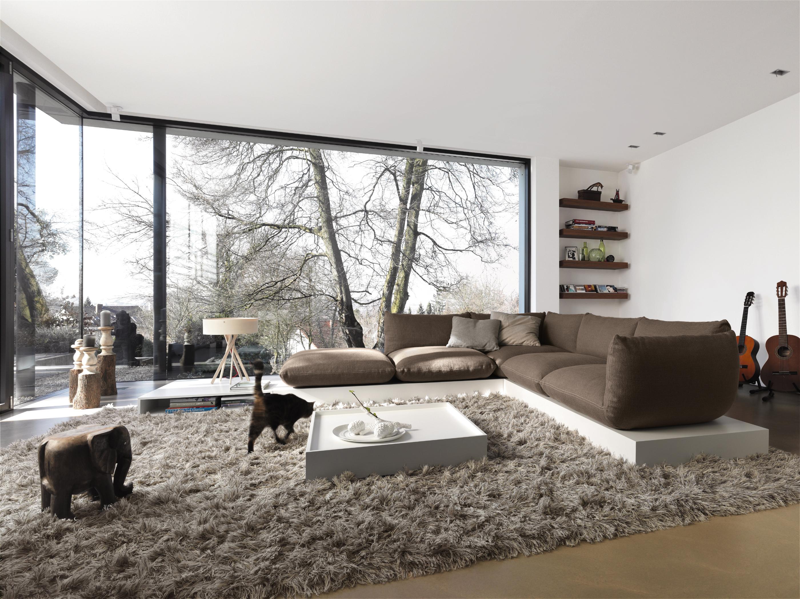 Langflorteppich und Sofa auf Podest #wandregal #ecksofa #designermöbel #ottomane #weißercouchtisch #braunessofa ©COR Sitzmöbel