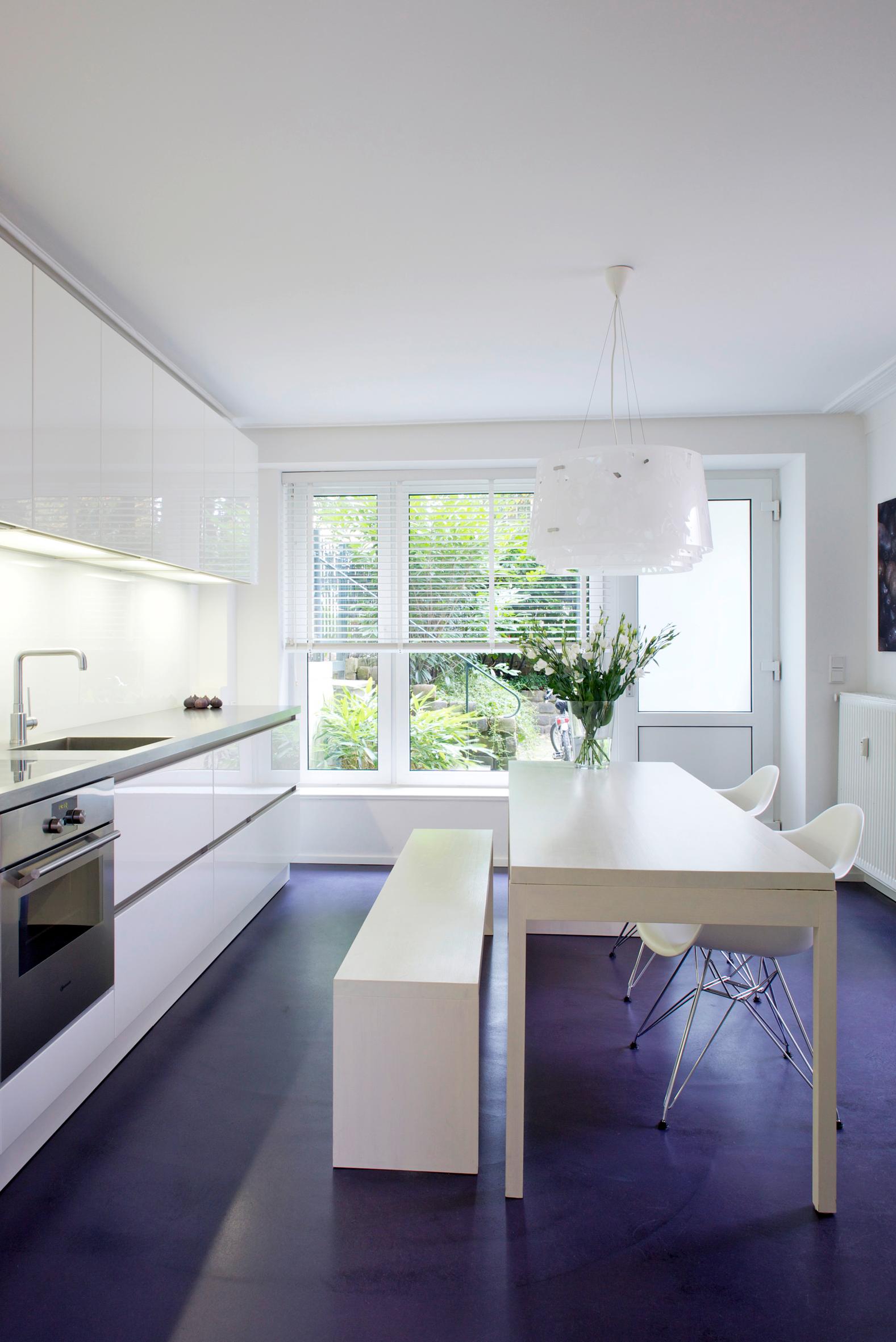 Moderne, weiße Küche mit farblich abgesetztem Fußboden #bodenbelag #esstisch #weißesitzbank #sitzbank #küchentisch #küchenbank #weißeküchemitdunklemfußboden ©burmester photography