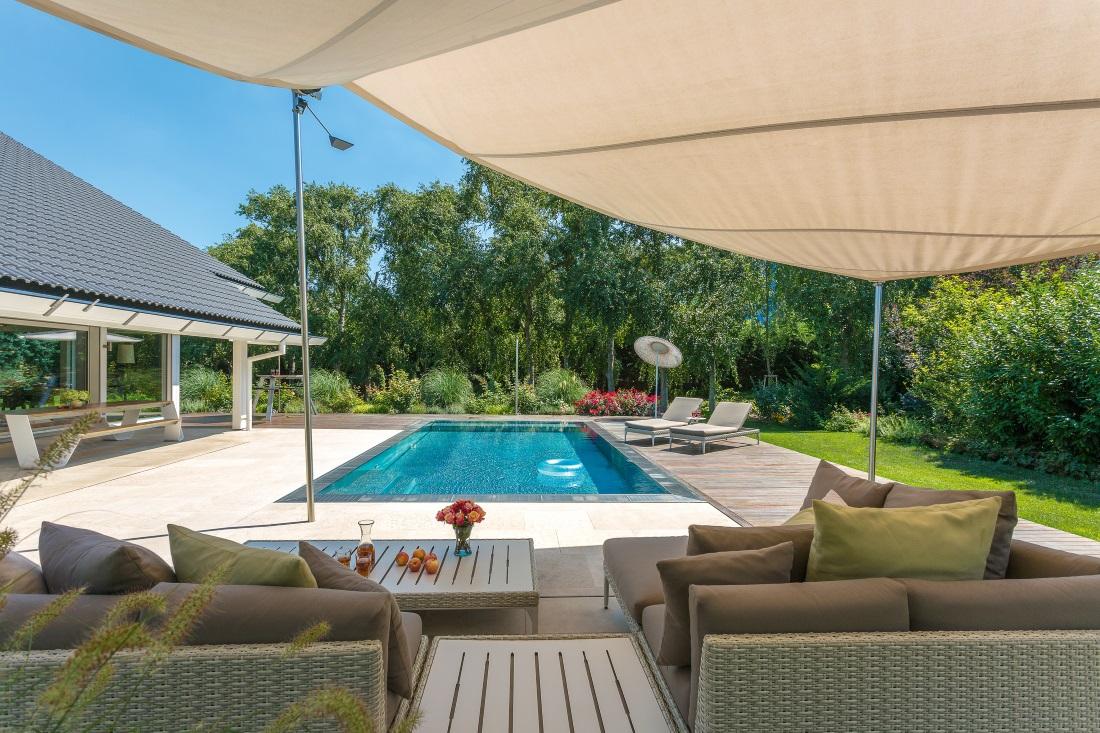 Sitzecke mit Blick auf den Pool #pool #terrasse #kissen #gartenliege #gartenmöbel #lounge #sitzecke #sonnenliege #sonnensegel #tisch ©HUF HAUS