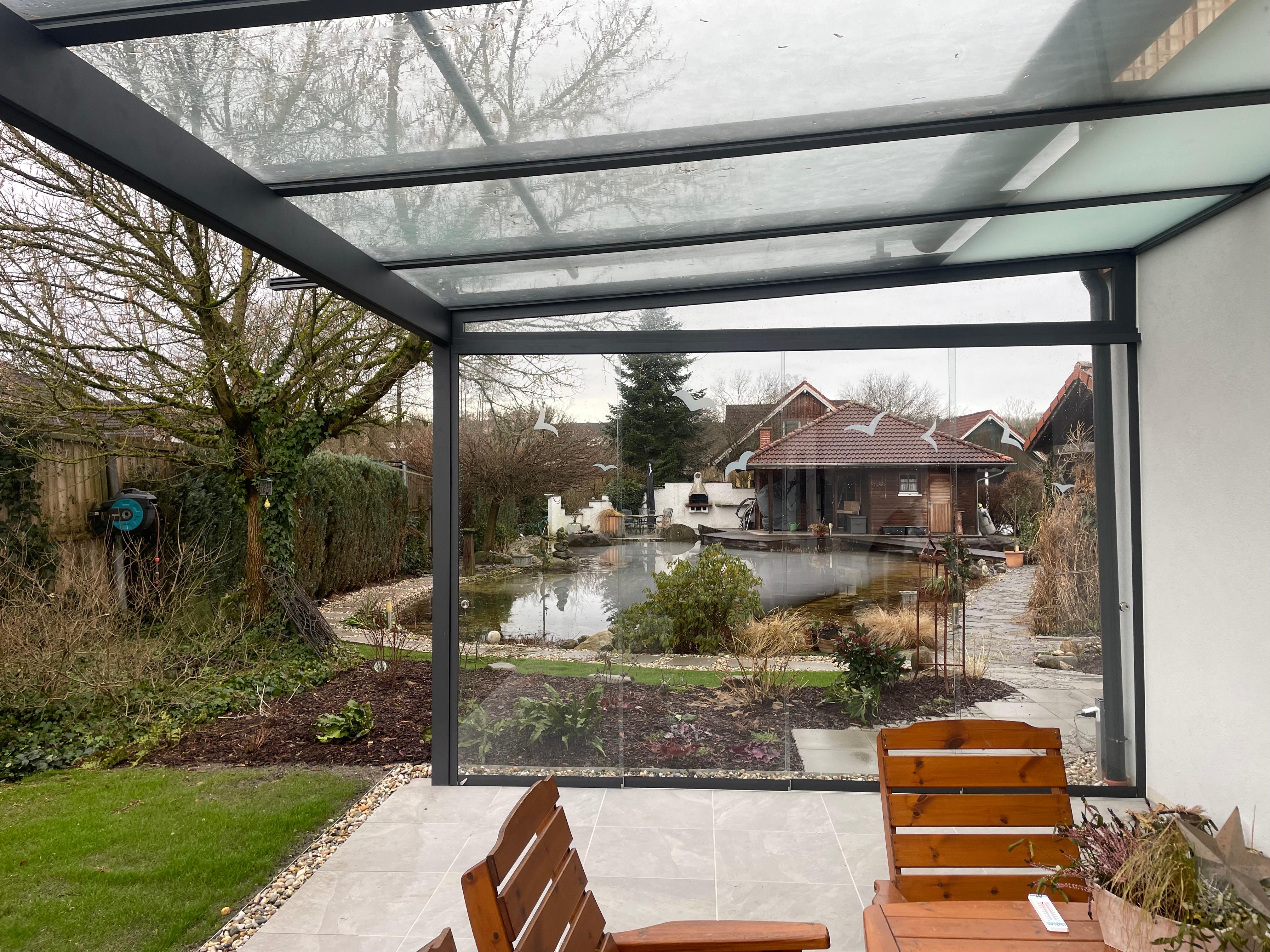 Terrassenüberdachung mit seitlichen Glasschiebetüren ist ideal, um sich vor Wind zu schützen. So kann man die Terrasse auch bei windigem Wetter genießen.