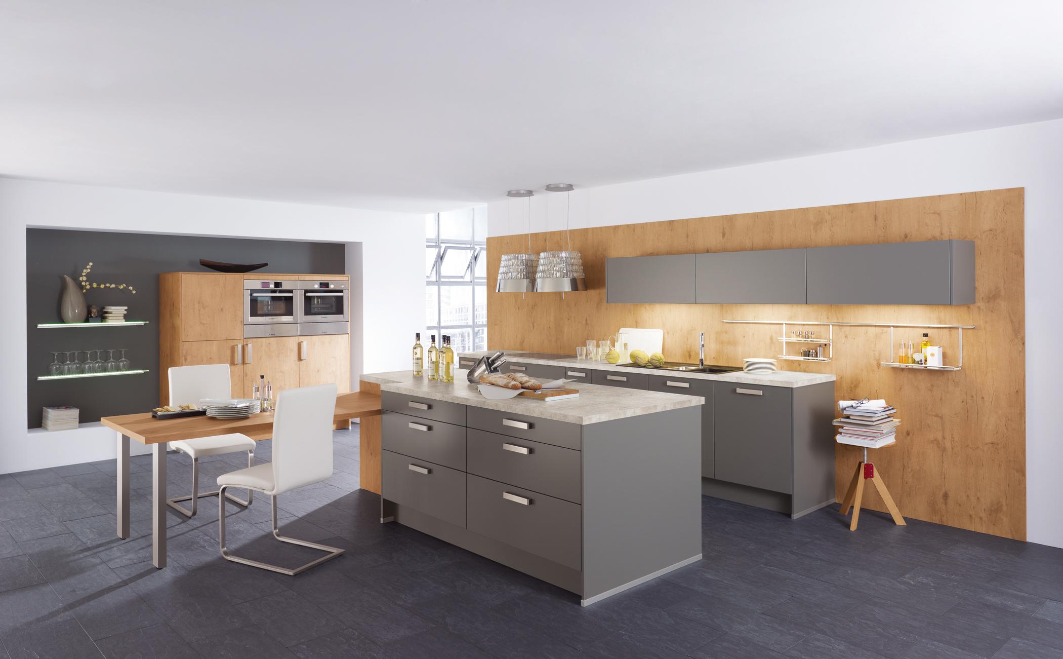 Wohnküche mit grauen Küchenschränken #wandverkleidung #esstisch #holzverkleidung #kücheninsel #grauerbodenbelag #holzwandverkleidung ©Wellmann/Alno AG