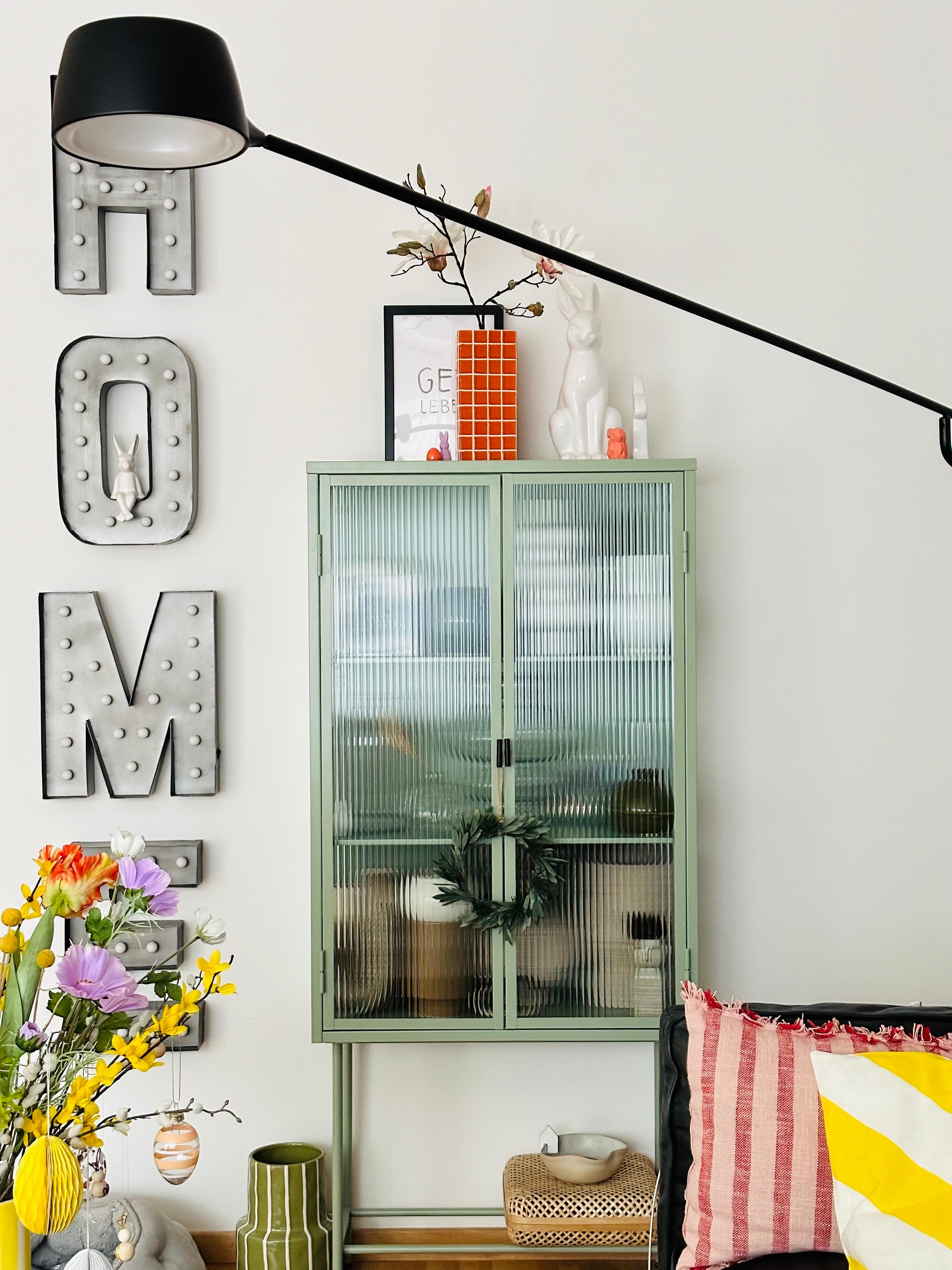 #wohnzimmer #vitrine #osterdeko #vase #farbenfroh #magnolie #licht #lampe #wanddeko #leuchtreklame #kissen #blumendeko #blumenliebe #bunt #poster #streifen #osterstrauch
