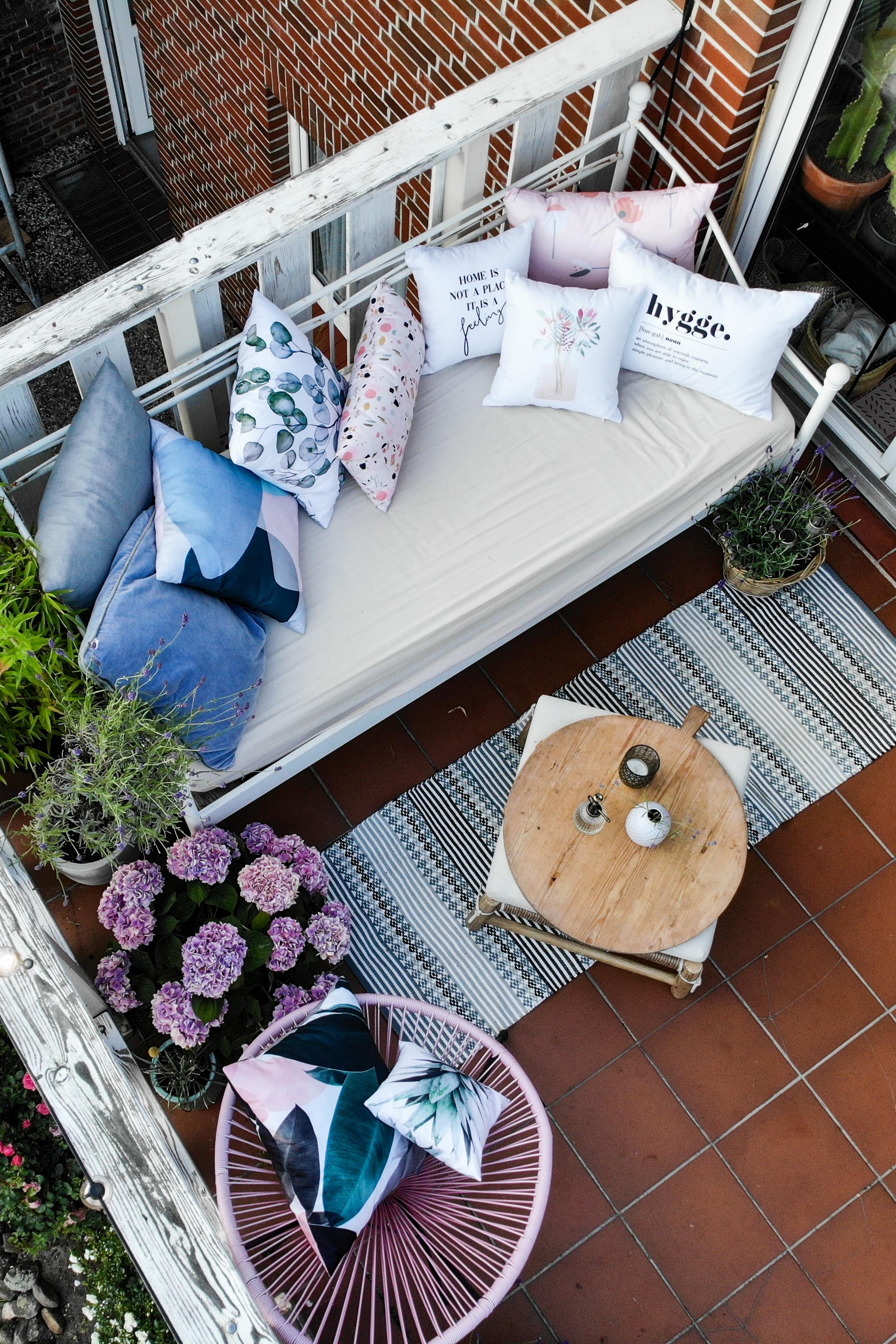 Auch der Balkon ist eine kleine Oase. Outdoorbed, Kissen, Outdoorteppich, Holzbrett und Blumen! #gartendeko #balkon 