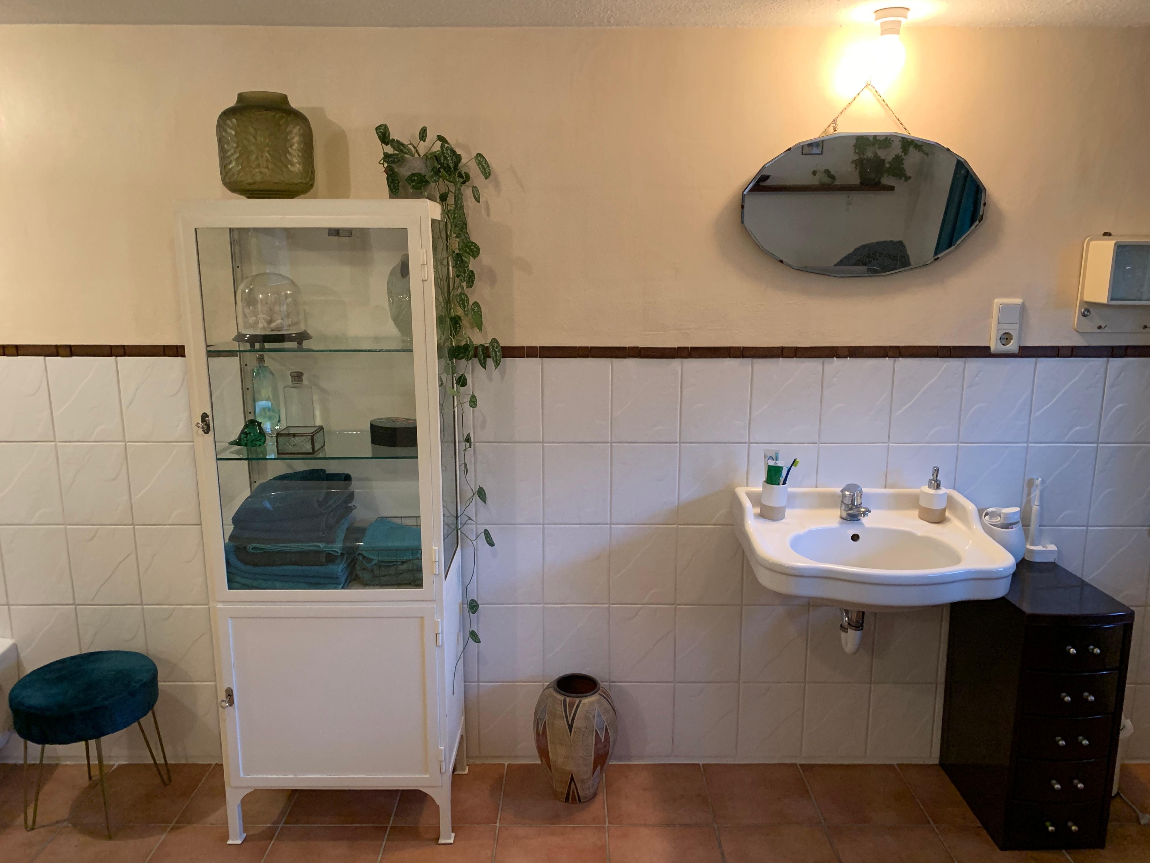 Badezimmer mit antiker Vitrine und Spiegel 