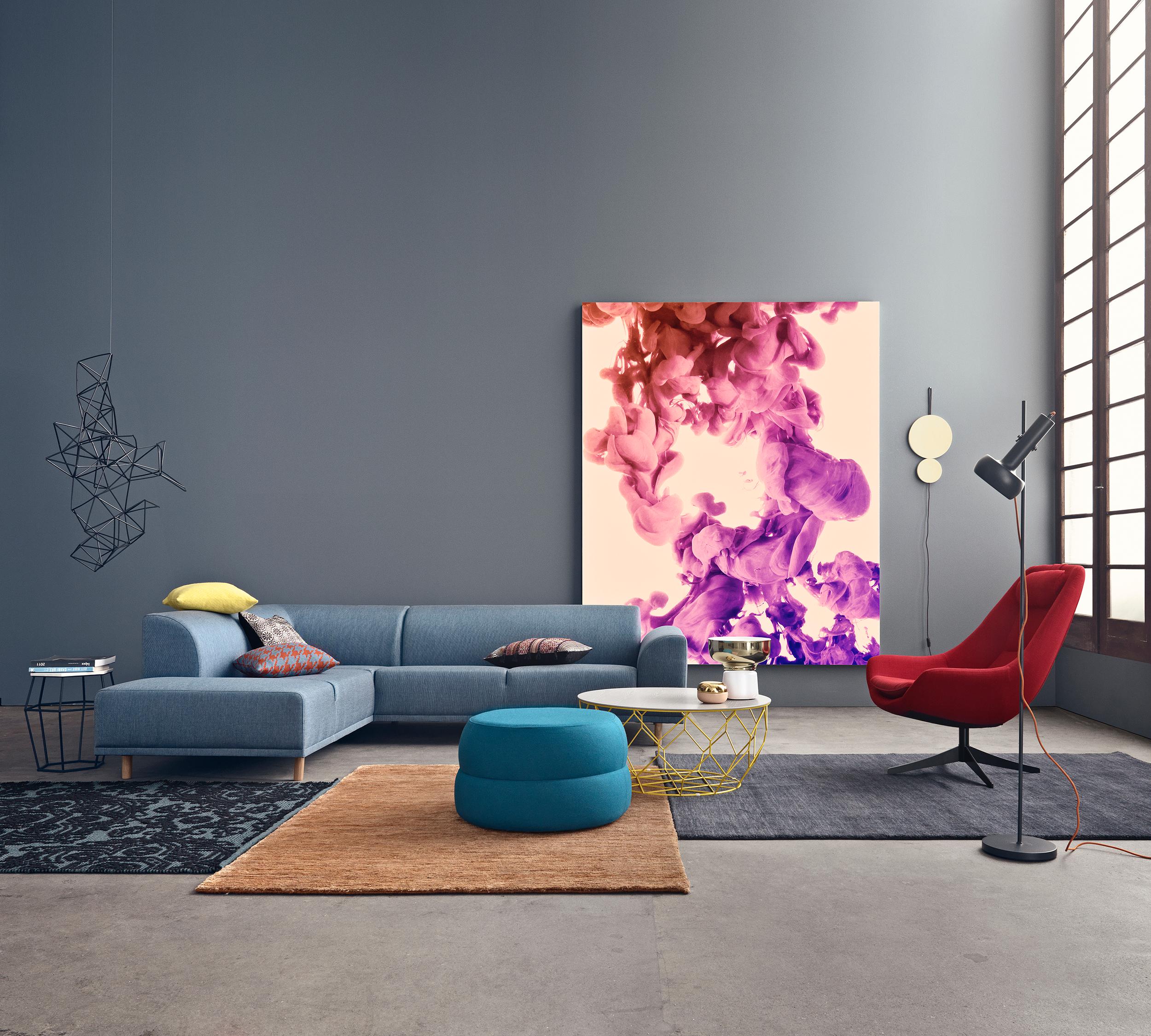 Buntes Bild vor einer grauen Wand #wandfarbe #sessel #kissen #rotersessel #grauewandfarbe #hohesfenster ©Bolia