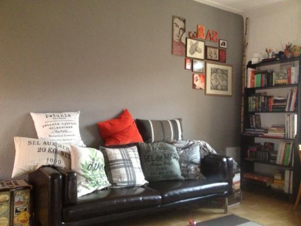 Das Wohnzimmer: Steingrau als Wandfarbe für eine Wand, viele Kissen und rote Elemente als Farbkick fürs Auge. #homestory