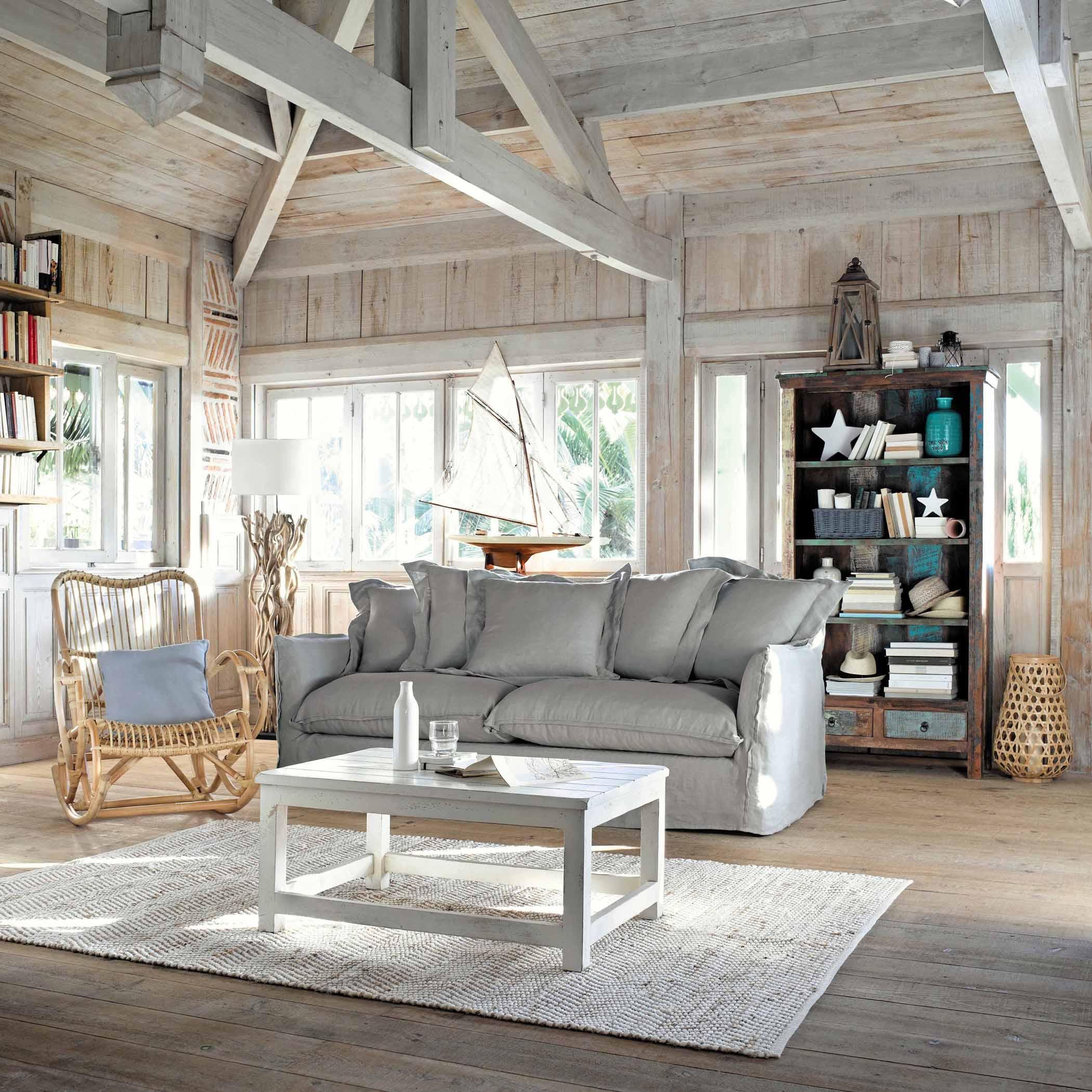 Maritimes Flair im Wohnzimmer #couchtisch #regal #teppich #shabbychic #dachbalken #schaukelstuhl #sofa #grauessofa #weißercouchtisch #maritim #beachlook ©Maisons du Monde