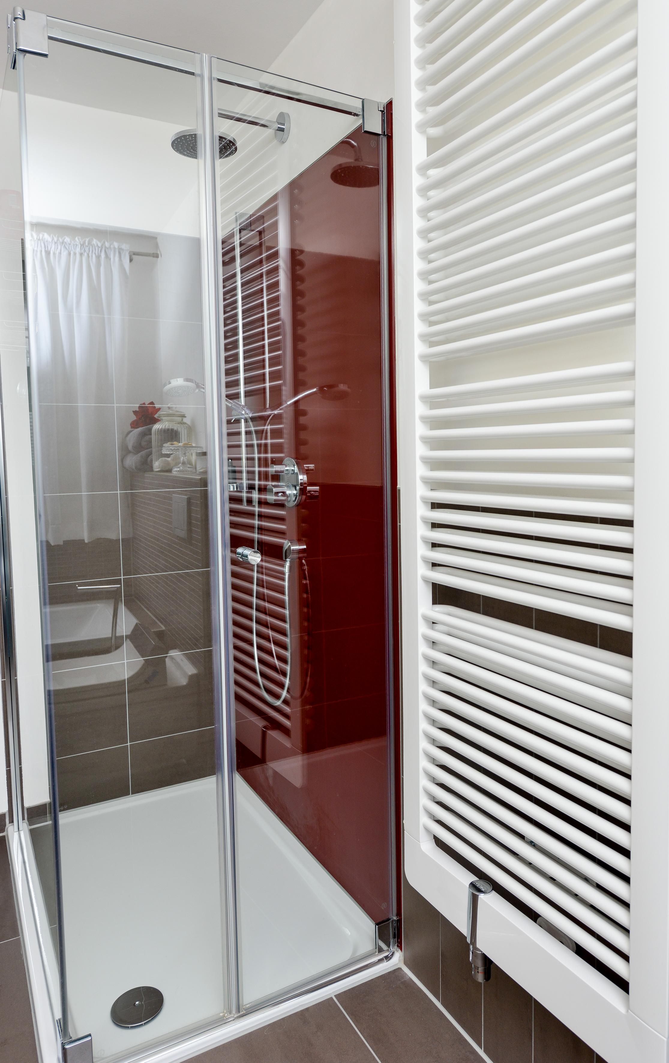 Rote Duschrückwand setzt farbigen Akzent #badezimmer #grauefliesen #handtuchheizkörper ©HEIMWOHL GmbH