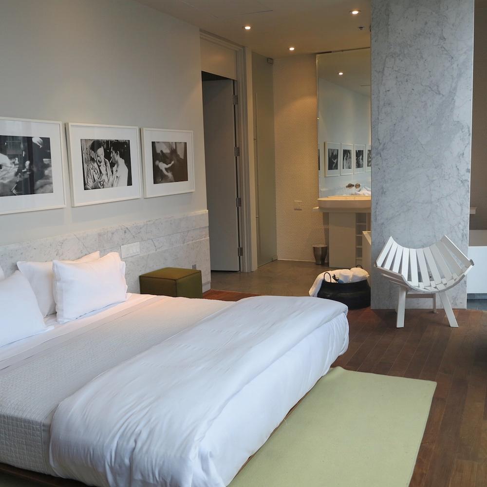 Schlafzimmer mit offenem Bad #bett #teppich #bilderrahmen #sessel ©Rasa en Détail