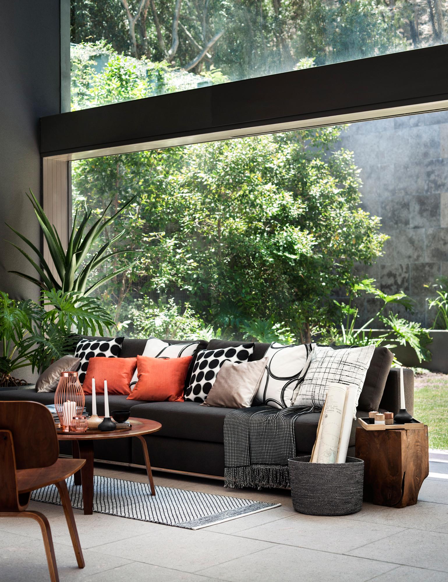 Schlichtes Sofa mit Dekokissen aufpeppen #couchtisch #teppich #wohnzimmer #tagesdecke #holzstuhl #panoramafenster ©H&M Home