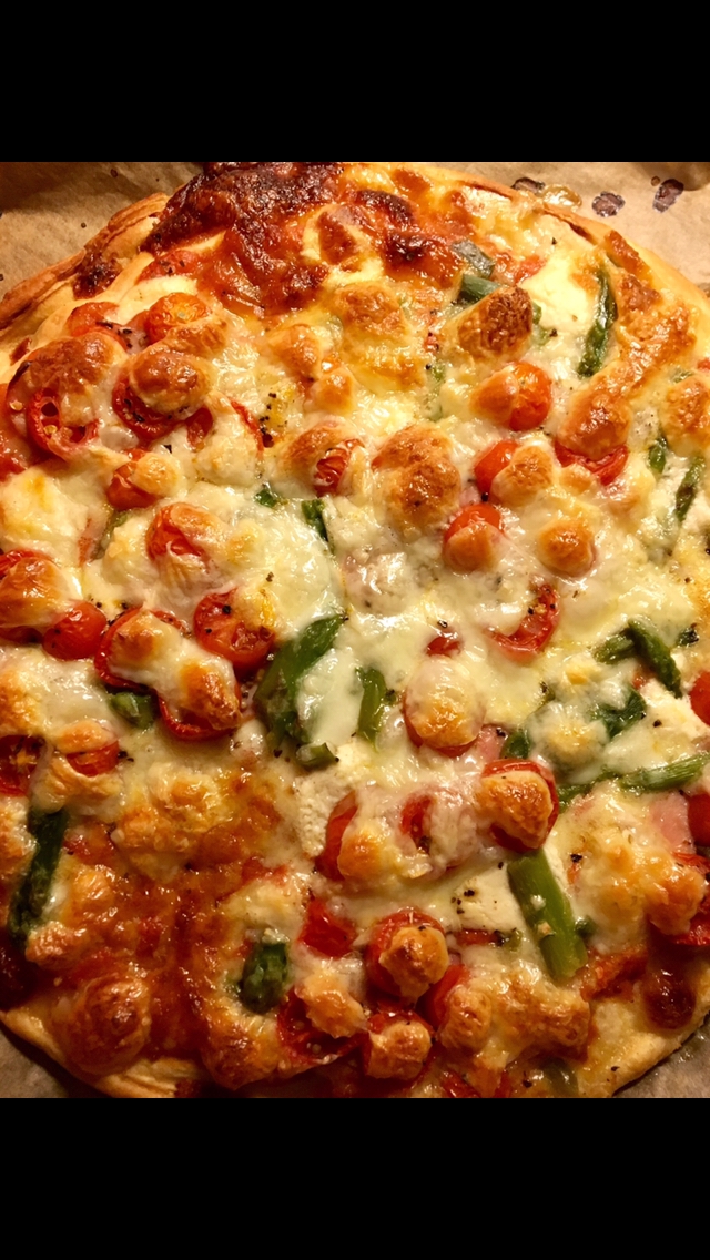 Selbstgemachte Pizza , belegt mit Kirschtomaten, Ruccola und einer Mischung aus drei Käsesorten.