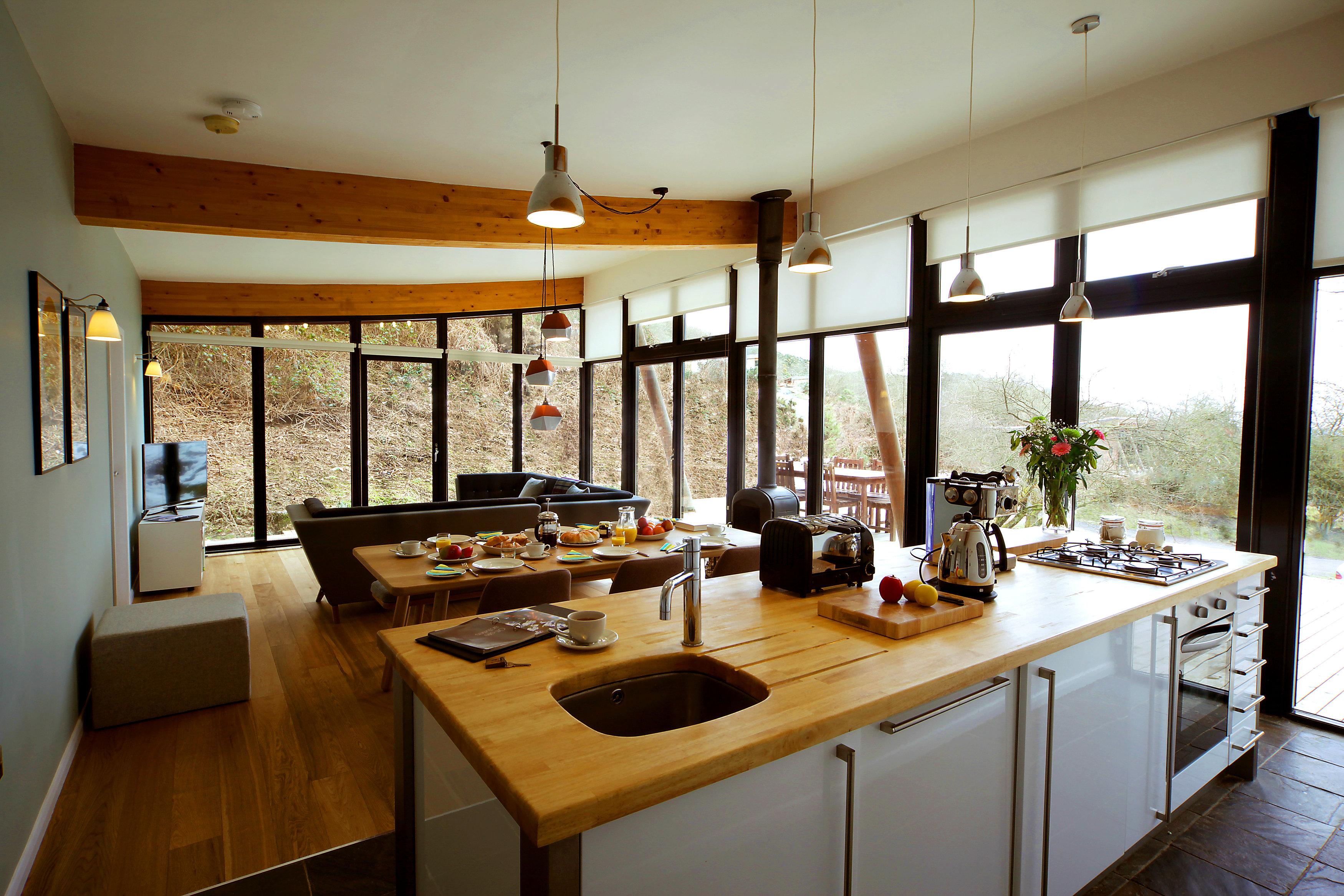 Wohnküche mit Holzarbeitsplatte #fensterfront #wohnküche #arbeitsplatte #wohnzimmer #esstisch #dachbalken #pendelleuchte #deckenbalken #sofa #hausgestaltung ©Another Country